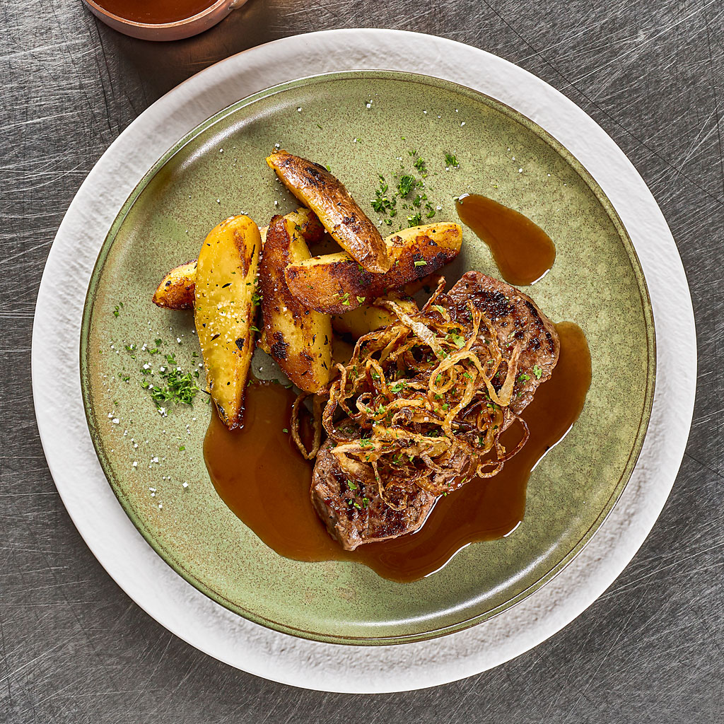 Телешки стек със сос от червено вино и билкови картофи.